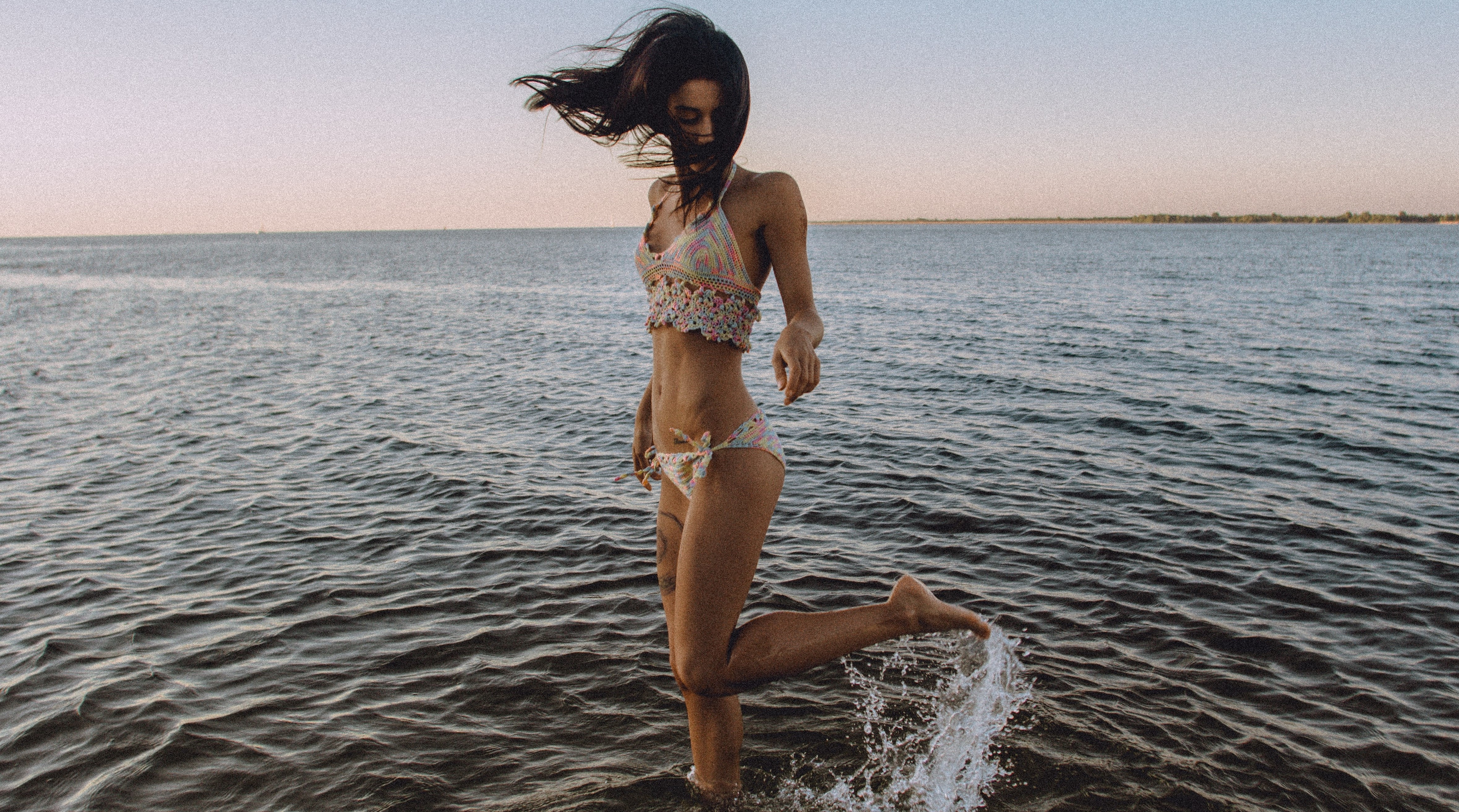 Frau tanzt glücklich am Strand im Wasser